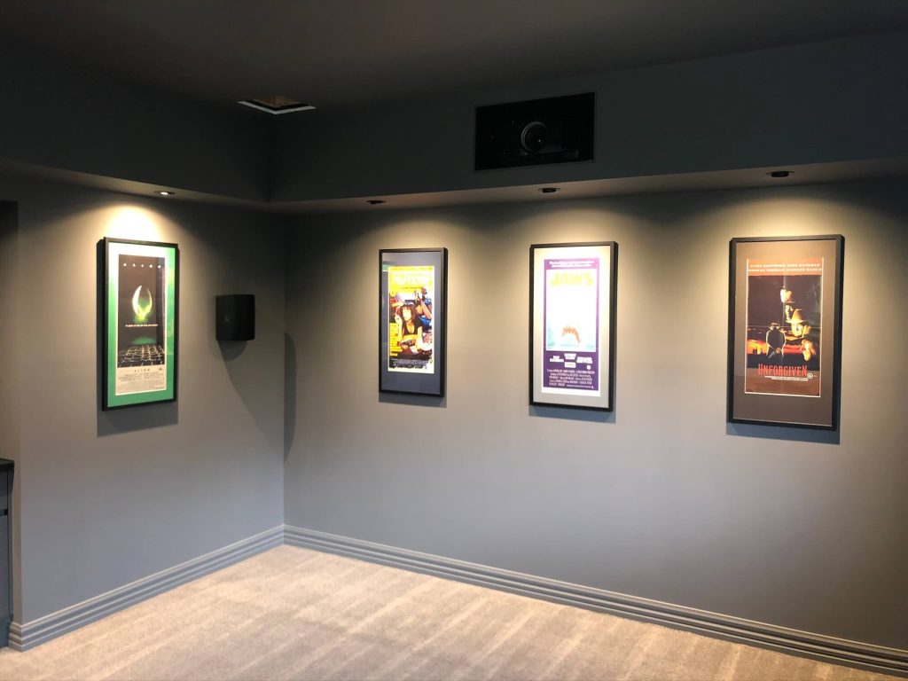 Movie room with framed movie posters and light setting with open cut section for projector for home cinema in Officer