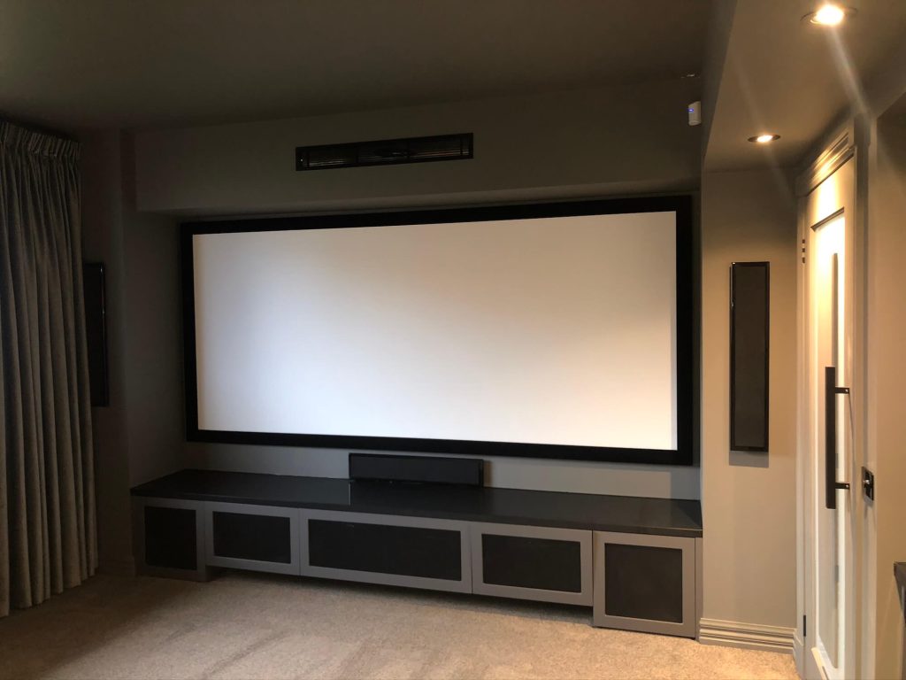 Officer in home cinema with large projector screen and entertainment area with surround sound speakers