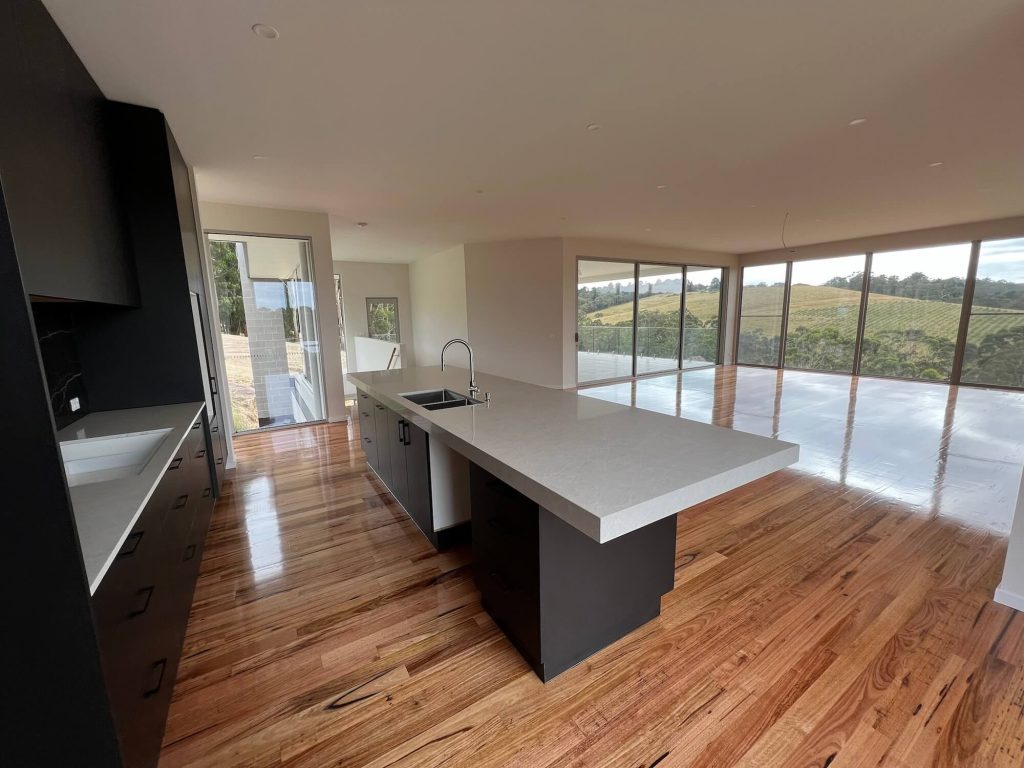Sleek and modern black and white kitchen with living room space open and scenic views of Narre Warren Victoria