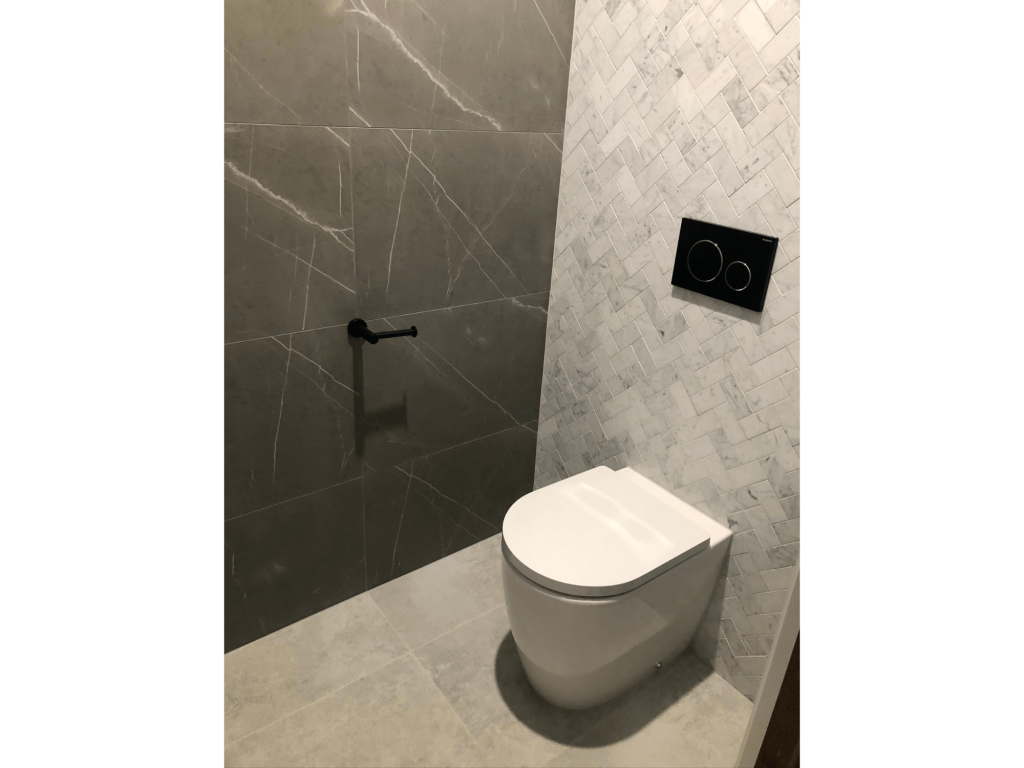 Stylish bathroom with modern toilet and push buttons in black finish with silver and grey tiles