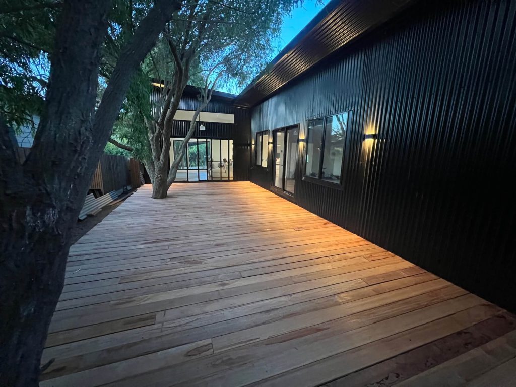 Trees connect with wooden decking next to home build with steel frame in Phillip Island